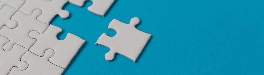 White jigsaw puzzle on blue background. Team business success partnership or teamwork.